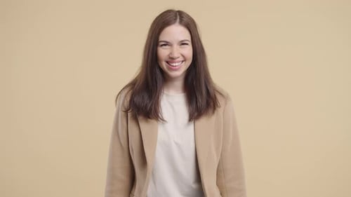 Smiling Woman Wearing a Tan Coat Over Beige Background