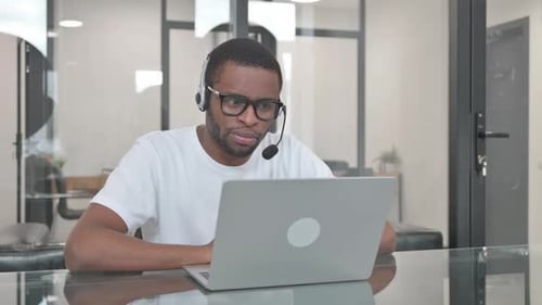 Young African Man with Headset Talking Online with Customer in Call Center