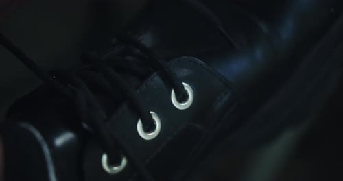 Young man tying the laces of his black leather British school shoes and then going for a walk.