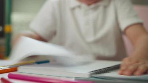 Boy Pulls to Tear Out Notebook Page with Drawing at Table