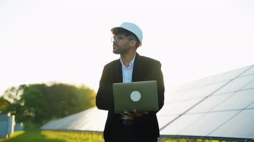 Engineer Working with Laptop in Solar Panel Farm