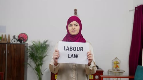 Muslim Woman in Hijab Scarf standing with Labour Law Poster