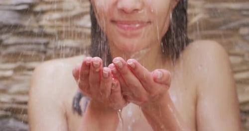 Biraciale Frau entspannt sich und duscht im Badezimmer