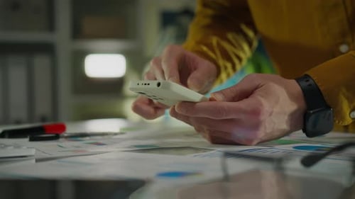 Person using Smartphone Over Business Documents