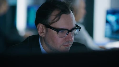 Porträt des gutaussehenden Experten mit Brille, der an einem Computer arbeitet. Im Hintergrund aus dem Fokus