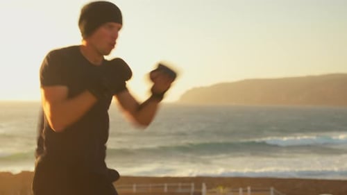 Male Athlete Practicing Boxing at Sunrise Near Ocean