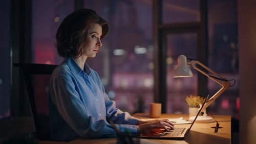 Woman Working on Laptop at Night in City Apartment