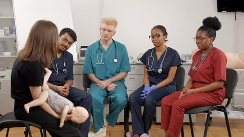 Medical professionals in training class observe demonstration with doll