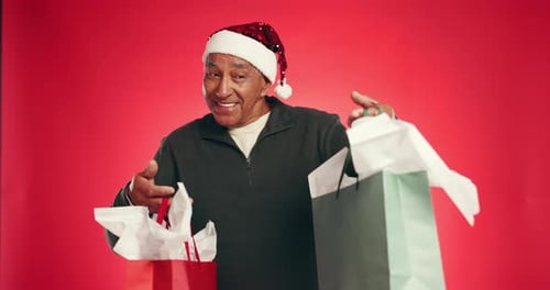 Christmas, face and old man in studio, gift and decision with holiday season on red background