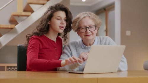 Young Adult Showing Senior Mother How to Use Computer