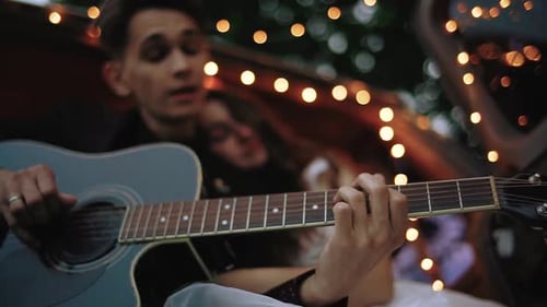 Glückliches Paar, Mann und Frau, singen, spielen Gitarre, entspannen sich und genießen die Freizeit