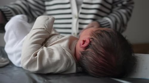 Infant Lying on Changing Table with Caregiver Nearby
