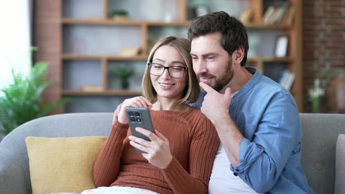 Excited Couple Celebrate Success Looking at Smartphone Indoors