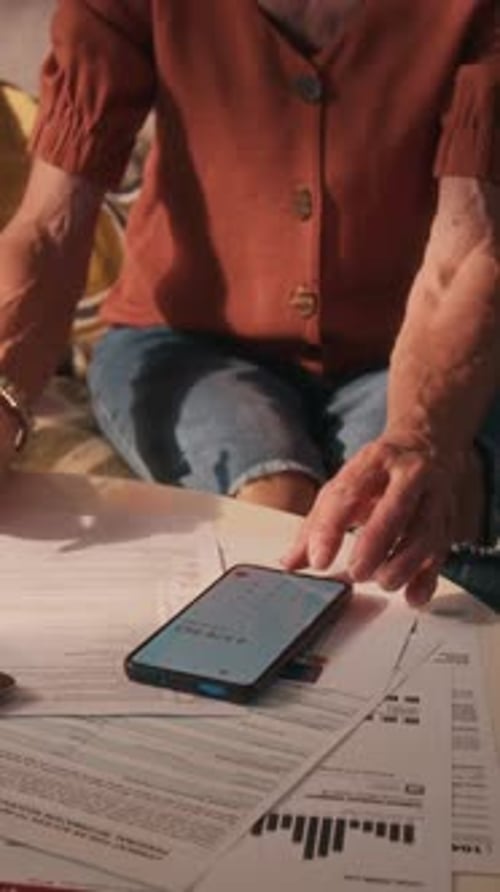 Mujer mayor enfocada en calcular los costos mensuales de los servicios públicos usando el teléfono