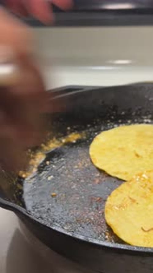 close up searing corn tortillas in cast iron pan