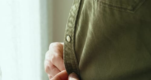 a man ties his green shirt close up