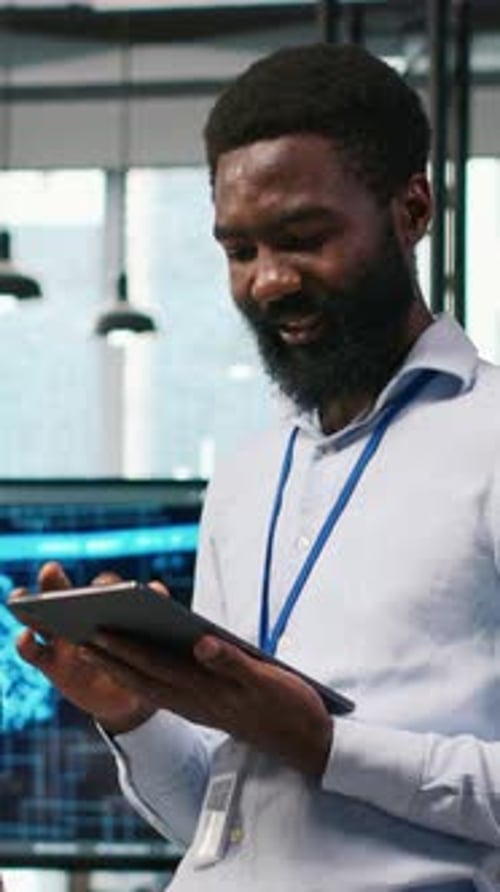 Smiling Man Uses Tablet in Workplace