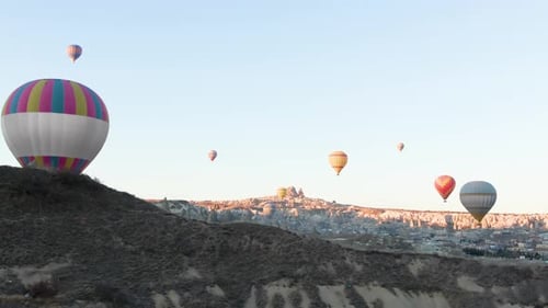 Hot Air Balloons Ascend Over Rocky Landscape