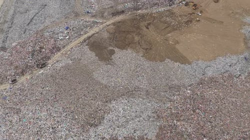 Aerial view of a large landfill with garbage trucks unloading waste