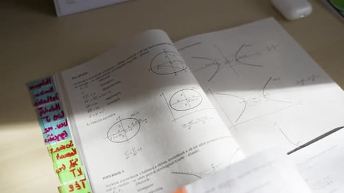 Livro de matemática aberto com diagramas e notas, abas coloridas visíveis na lateral