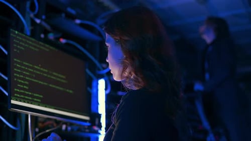Woman Working with Computer Code in Dark Server Room