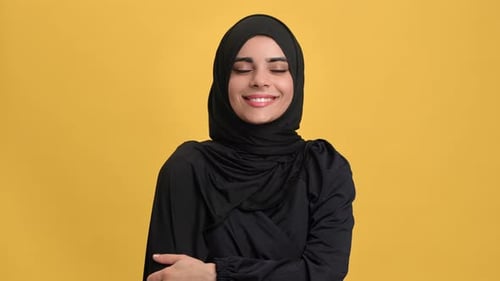 Portrait Smiling Beautiful Muslim Woman in Black Hijab Posing Isolated on Orange Studio Closeup
