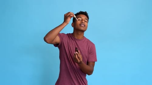 Man Applying Moisturizing Serum to His Face in Studio