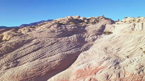 Vista aérea inclinada desde una grúa de las montañas con rayas naranjas y blancas en Yant Flats, Utah, cerca de St. George.
La