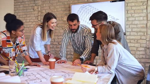 Group of young business people discussing architectural designs in office.
