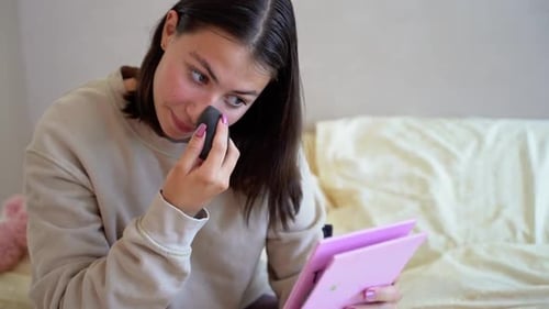 Young Woman Applies Makeup with a Sponge at Home