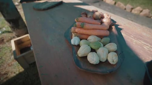 Fresh vegetables lying on wooden cutting board: carrots, onions and chayotes
