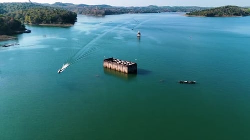 Wooden boats go around an underwater temple that is in the center of a beautiful blue lake that was