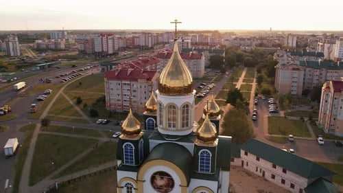 Aerial View of Beautiful Orthodox Church with Golden Domes at Crossroads in the City on Summer Day