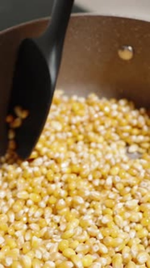 Vidéo verticale. Préparation du pop-corn, les grains sont mélangés dans la casserole sur la cuisinière à
gaz.