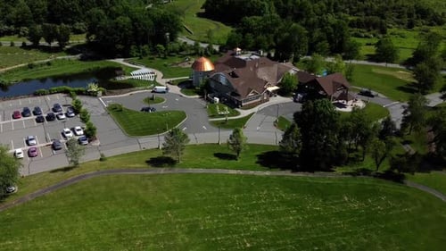 Drone flying over a banquet house for celebrations and weddings, surrounded by green land and trees.