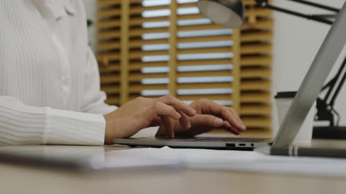 hands typing on a laptop keyboard at home office