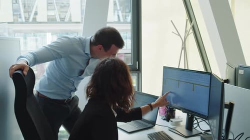 Two millennials in a corporate environment solve a data problem on an office computer