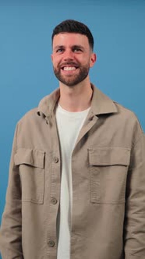 Smiling Man with Arms Crossed in Front of Blue