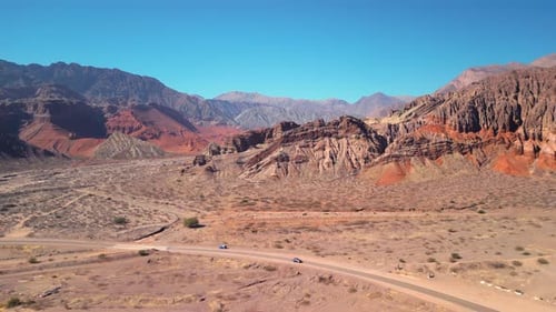 Aerial view drone flying over scenic red rocky mountains landscape with a clear blue sky.