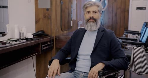Mature Bearded Man in Barbershop Relaxing in Barberchair