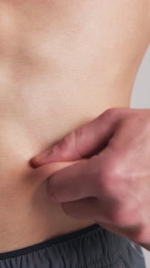 Hands, person and pinch abdomen for diet progress, nutrition or intermittent fasting in studio