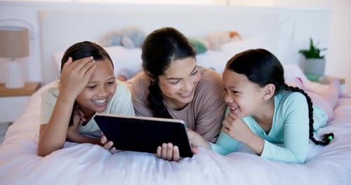 Smiling Family Using a Tablet on the Bed