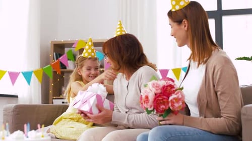 Family celebrating birthday with flowers and gift