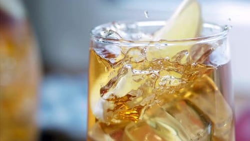 Lemon Slice Splashing into Drink with Ice Cubes