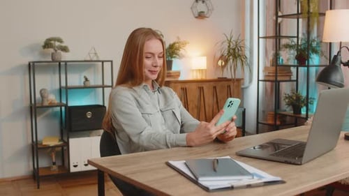 Woman Using Smartphone at Desk in Home Office