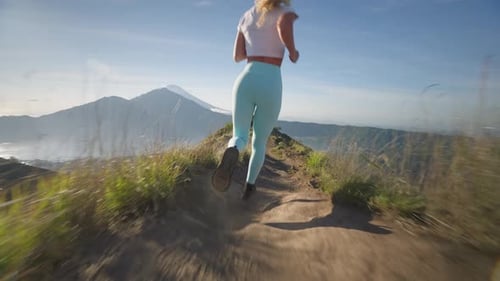 Fearless blond woman running fast on mountain ridge of Batur, high on life