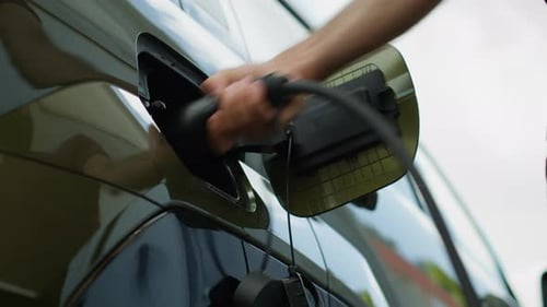 Close Up of Driver Disconnecting EV Vehicle From Charging Dock Low Angle Shot