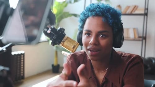 Jovem blogueira afro-americana positiva se senta na mesa com microfone