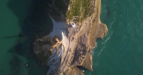 Portrait drone shot directly above Castle Point lighthouse panning across the rocky coastline.