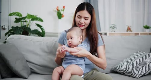 Woman Holding Infant on Couch Indoors